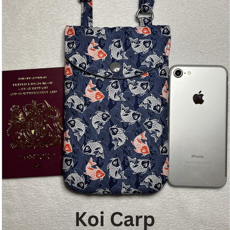 May include: A navy blue phone bag with a flap closure, featuring a pattern of white and orange koi fish. The bag has adjustable straps and a silver snap closure. The text "Koi Carp" is at the bottom of the image.