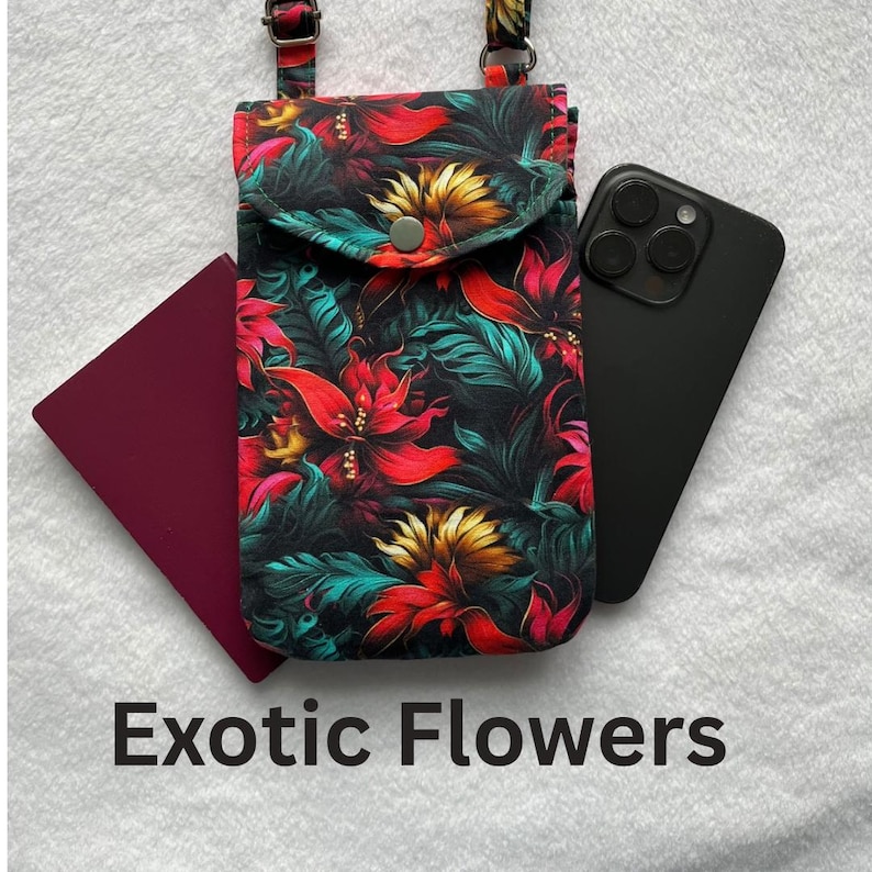 May include: A floral print phone crossbody bag with a burgundy passport and a black smartphone. The bag features a vibrant pattern of red, yellow, and teal flowers on a black background. The text "Exotic Flowers" is displayed at the bottom.