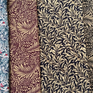 May include: Four fabric swatches with different floral patterns. The first swatch is a dark blue fabric with a white and red floral pattern. The second swatch is a burgundy fabric with a gold floral pattern. The third swatch is a dark blue fabric with a gold floral pattern. The fourth swatch is a black fabric with a gold floral pattern.