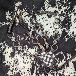 May include: A brown and silver horse bridle with a black and white checkered breastplate. The bridle features silver rings and decorative squares with black and white accents. The text "Partyhorsetack" is written across the image.
