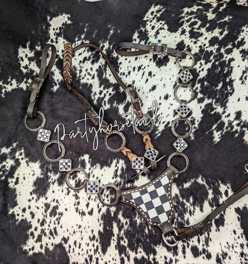 May include: A brown and silver horse bridle with a black and white checkered breastplate. The bridle features silver rings and decorative squares with black and white accents. The text "Partyhorsetack" is written across the image.