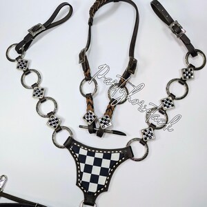 May include: A horse tack set featuring a dark brown leather bridle with silver-tone hardware and a black and white checkered breast collar. The set includes a braided browband and decorative accents.