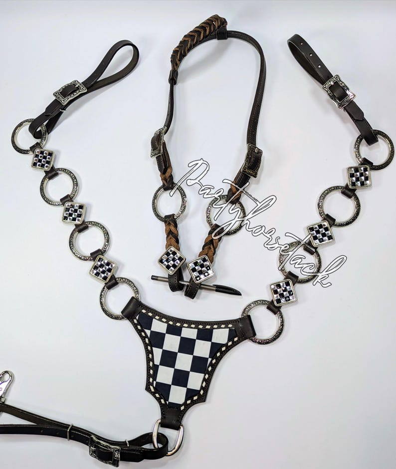 May include: A horse tack set featuring a dark brown leather bridle with silver-tone hardware and a black and white checkered breast collar. The set includes a braided browband and decorative accents.