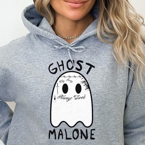 May include: Gray hooded sweatshirt with a white ghost graphic and the text "Ghost Malone" printed on the front. The ghost has a barbed wire tattoo around its head and the text "Always Tired" inside.