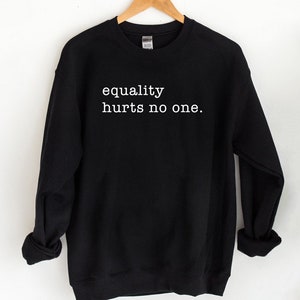 May include: Black sweatshirt with the text "equality hurts no one" in white.