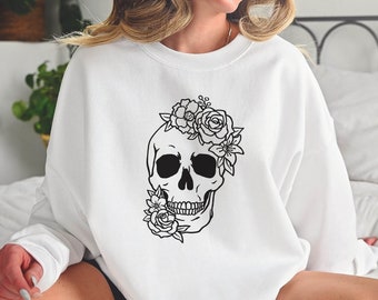 May include: White sweatshirt with a black and white graphic of a skull with flowers on the front.