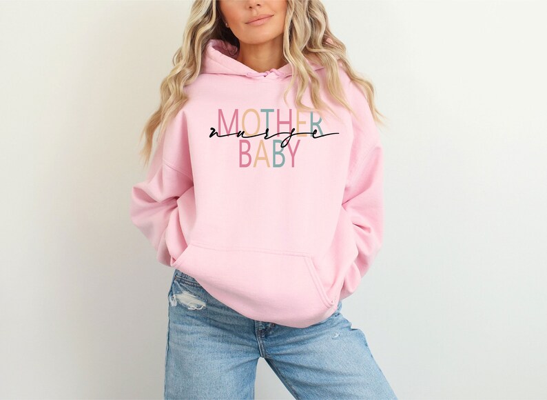 Puede incluir: Sudadera rosa con el texto "MOTHER" en colores arco&iacute;ris y "BABY" en azul y rosa. El texto est&aacute; escrito en una fuente cursiva.