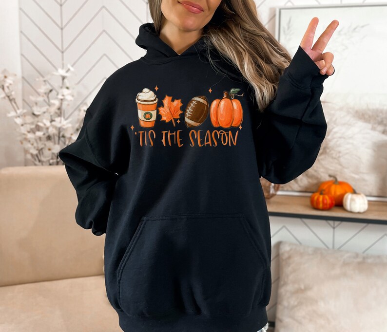 May include: Black hoodie with a graphic of a coffee cup, leaves, a football, and a pumpkin. The text "'Tis the season" is below the graphic.