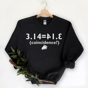 May include: Black sweatshirt with white text that reads "3.14=PI.E (coincidence?)" and a white pie slice icon.