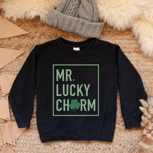 May include: Black sweatshirt with a green shamrock and the text "MR. LUCKY CHARM" in a white box.