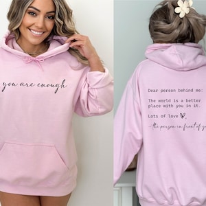 May include: Pink hoodie with the text "you are enough" on the front and "Dear person behind me: The world is a better place with you in it. Lots of love, - the person in front of you" on the back.