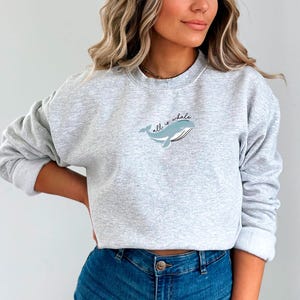 May include: A gray sweatshirt with a whale graphic and the text "all is whale" on the front.