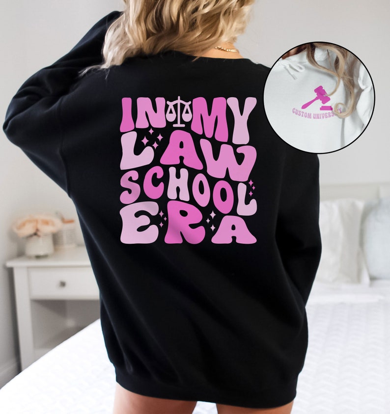 May include: Black sweatshirt with a pink graphic that says "In My Law School Era" with a scale of justice symbol.