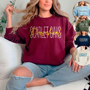 May include: A maroon sweatshirt with the text "Scarlet Oaks Preschool" in white and gold lettering.