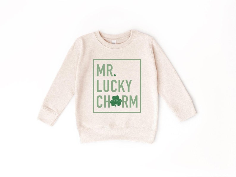 May include: A light beige sweatshirt with a green shamrock and the text "MR. LUCKY CHARM" in a green box.