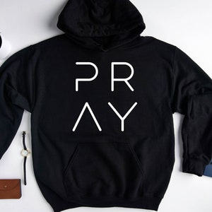 May include: Black hoodie with a white graphic that says "PRAY" in a modern font.