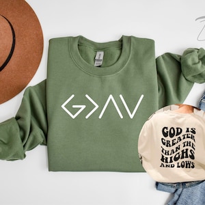 以下が含まれることがあります： 白い文字で「G>A>V」と書かれた緑色のスウェットシャツ。ベージュのスウェットシャツには黒い文字で「God is greater than the highs and lows」と書かれている。