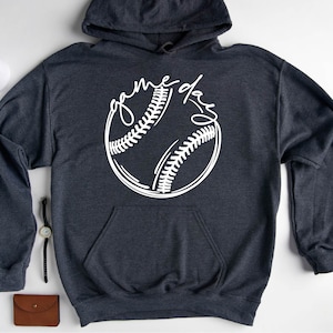 May include: Dark heather grey hoodie with a white baseball graphic and the text "game day" written in a script font.