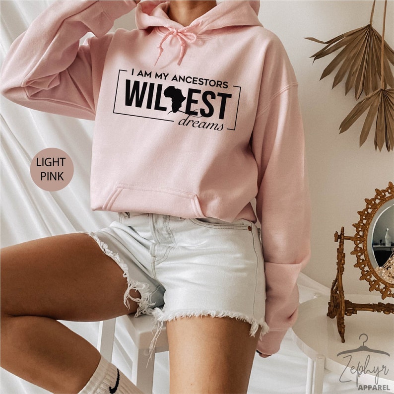 May include: A light pink hooded sweatshirt with the text "I am my ancestors wildest dreams" and a black silhouette of the continent of Africa.