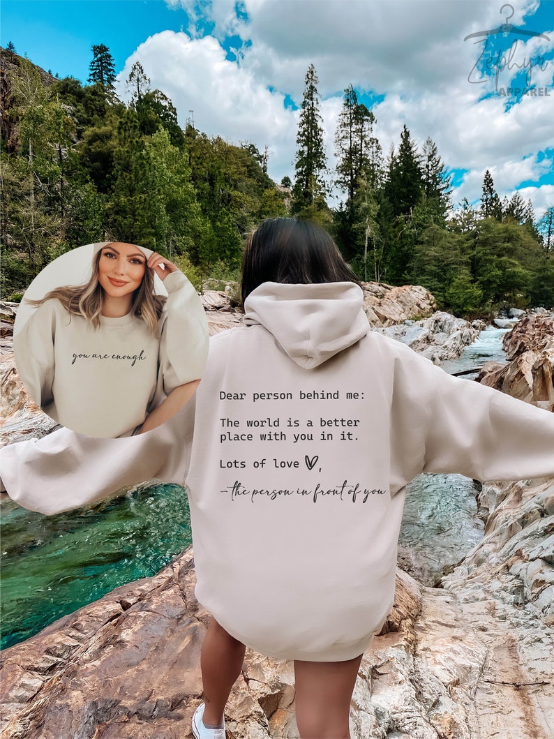 May include: A beige hooded sweatshirt with the text "Dear person behind me: The world is a better place with you in it. Lots of love, - the person in front of you" printed on the back.