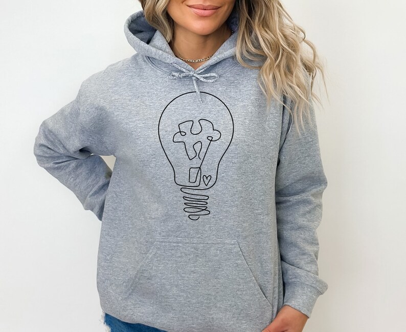 May include: A gray hooded sweatshirt with a black line drawing of a lightbulb with a heart in the center. The lightbulb is drawn in a simple, minimalist style.