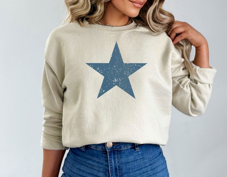 May include: A light beige sweatshirt with a distressed blue star graphic.