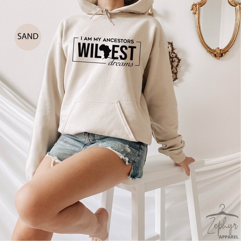 May include: A sand-colored hoodie with a black graphic that says "I am my ancestors wildest dreams" with an outline of the continent of Africa.