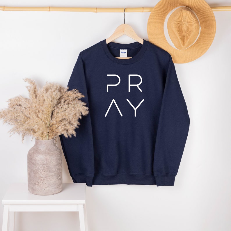 May include: Navy blue sweatshirt with the word "PRAY" printed in white on the front.