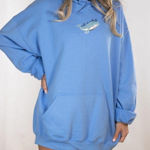 May include: A light blue oversized hoodie with a whale graphic and the text "all is whale".