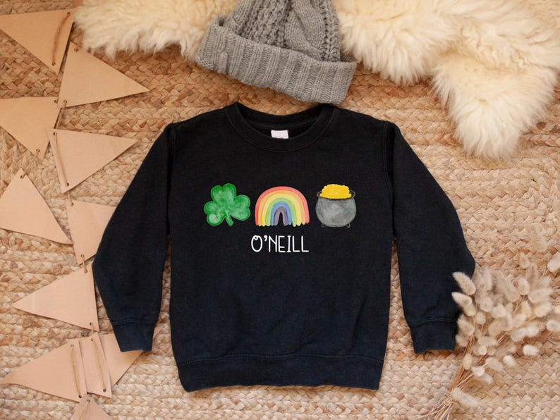 May include: Black sweatshirt with a green shamrock, rainbow, and pot of gold graphic. The text "O'NEILL" is printed below the graphic.