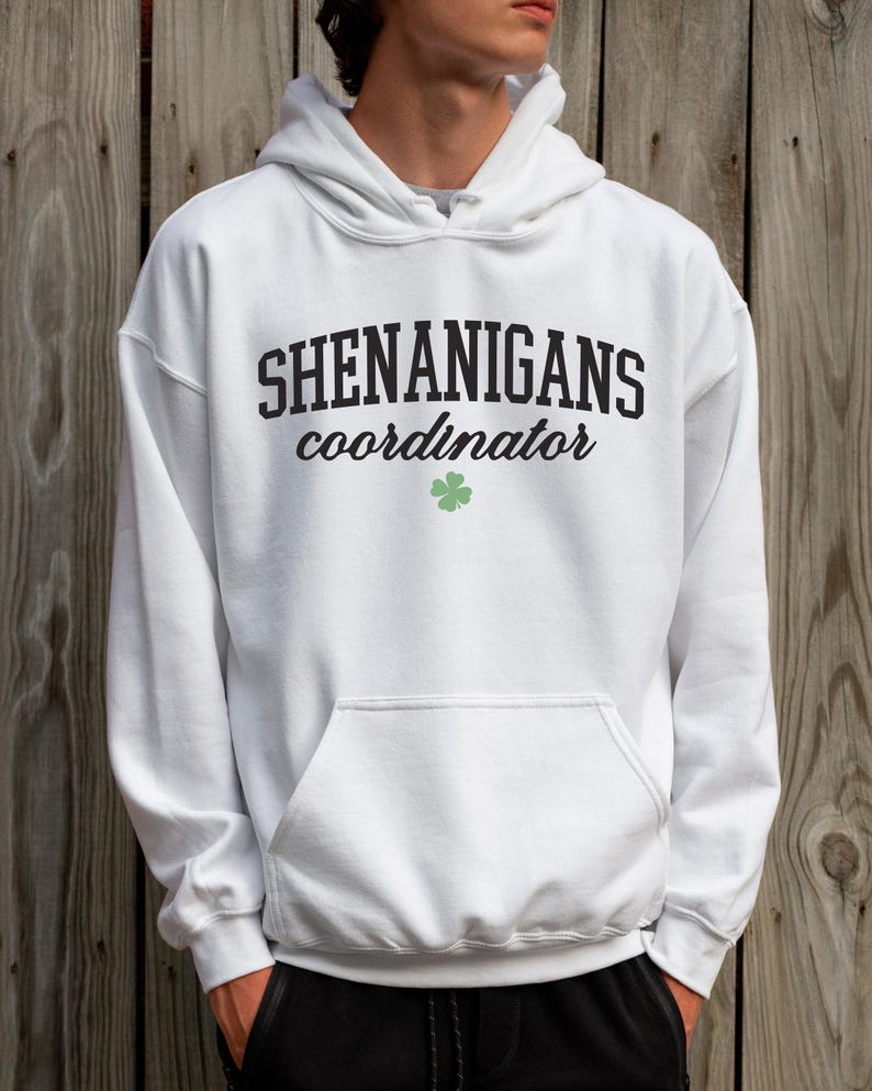 May include: White hooded sweatshirt with the text "Shenanigans coordinator" in black lettering and a green four-leaf clover.