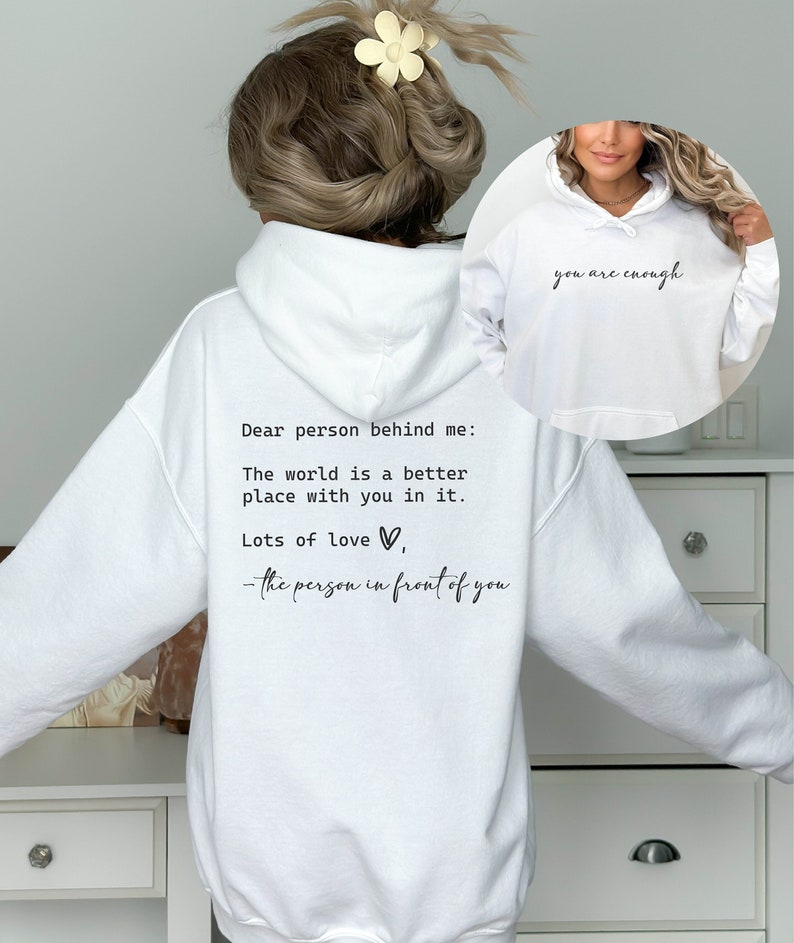 May include: White hooded sweatshirt with the text "Dear person behind me: The world is a better place with you in it. Lots of love, - the person in front of you" printed on the back. The front of the sweatshirt has the text "you are enough" printed on it.