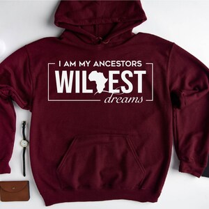 May include: Maroon hoodie with a white graphic that says "I am my ancestors wildest dreams" with an outline of the continent of Africa.