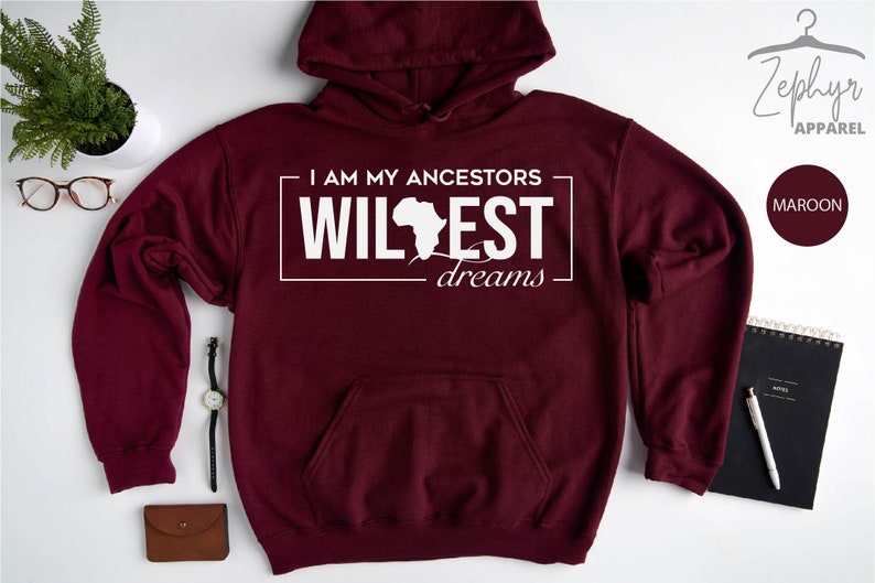 May include: Maroon hoodie with a white graphic that says "I am my ancestors wildest dreams" with an outline of the continent of Africa.
