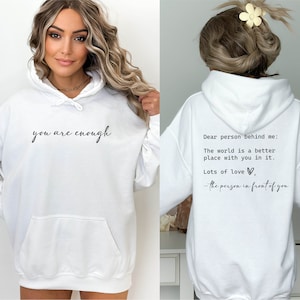 May include: White hooded sweatshirt with the text "you are enough" printed on the front and "Dear person behind me: The world is a better place with you in it. Lots of love, - the person in front of you" printed on the back.
