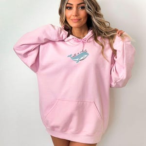 May include: A pink oversized hoodie with a whale graphic and the text "all is whale" on the front.