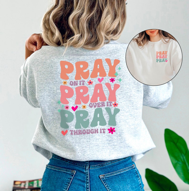May include: A grey sweatshirt with a colourful graphic on the back that says "Pray on it, Pray over it, Pray through it".