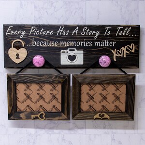 May include: A wooden sign with the text "Every Picture Has A Story To Tell... ...because memories matter" and two wooden picture frames with cork inserts. The sign has a lock, camera, and heart shapes.