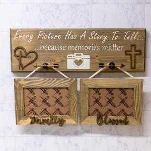 May include: A rustic wooden sign with the text "Every Picture Has A Story To Tell... because memories matter". The sign features a cross, a heart, and a camera. Two rustic wooden picture frames hang below the sign, one with the word "Family" and the other with the word "Blessed".