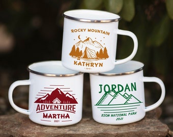 Puede incluir: Tres tazas de camping de esmalte blanco con diferentes diseños. La taza superior tiene una escena de montaña marrón con el texto "ROCKY MOUNTAIN" y "KATHRYN 2019". La taza del medio tiene una escena de montaña roja con el texto "ADVENTURE MARTHA 2021". La taza inferior tiene una escena de montaña verde con el texto "JORDAN ZION NATIONAL PARK 2021".