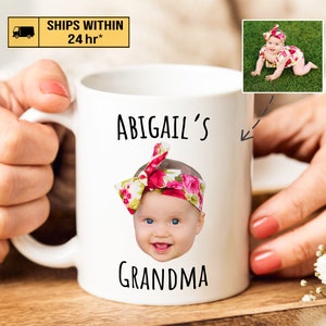 May include: White ceramic mug with a black and white design that says "Abigail's Grandma". A photo of a baby girl with a floral headband is centered on the mug.