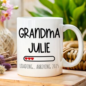 May include: White ceramic mug with black text that reads "Grandma Julie" and a progress bar with three red hearts that says "Loading... Arriving 2025".