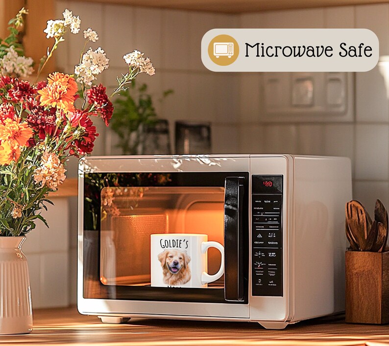 Op de afbeelding: Een witte keramische mok met een foto van een golden retriever en de tekst "Goldie's" staat in een magnetron. De magnetron is wit en heeft een digitaal display. De afbeelding bevat ook een vaas met bloemen en de tekst "Microwave Safe".