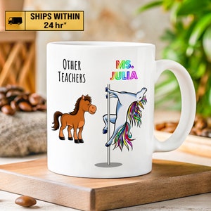 May include: White ceramic coffee mug with a brown horse and a rainbow unicorn on a pole. The text on the mug reads "Other Teachers" and "Ms. Julia".