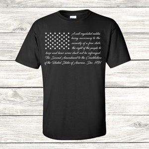 May include: Black t-shirt featuring a white American flag design and the text "A well regulated militia being necessary to the security of a free state, the right of the people to keep and bear arms shall not be infringed. The Second Amendment to the Constitution of the United States of America. Dec. 1791."