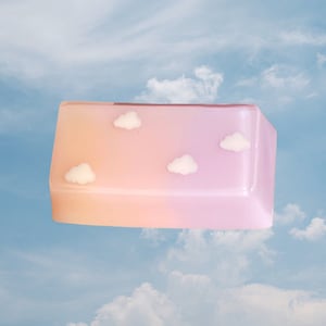 May include: A pink and orange gradient keycap with white cloud designs. The keycap is a rectangular shape and has a glossy finish.