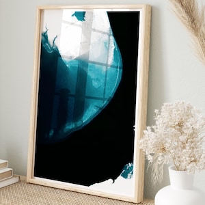 May include: Abstract art print in a wooden frame. The artwork features a dark teal and black design. The framed art is displayed on a light wood bench with woven baskets and a white vase with dried flowers. A candle and books are also on the bench.