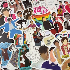 May include: A selection of vibrant stickers showcasing illustrations of a singer in various poses and outfits. The stickers include images of the singer with a rainbow flag, playing a guitar, and wearing different attire. Some stickers have text, including "HARRY STILES" and "WATERMELON SUGAR."