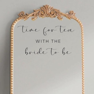 May include: A gold ornate mirror with a vinyl decal that reads "Time for tea with the bride to be". The mirror is surrounded by a beaded border. Below the mirror is a smaller mirror with a bee logo and the text "Bee's Vinyl Co.". The bottom mirror has a vinyl decal that reads "Vinyl Decal Any Size & Color".
