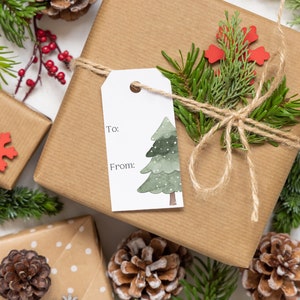 May include: A brown gift box wrapped with twine and decorated with a green pine sprig, a red snowflake, and a watercolor illustration of a Christmas tree. The gift tag says "To:" and "From:".